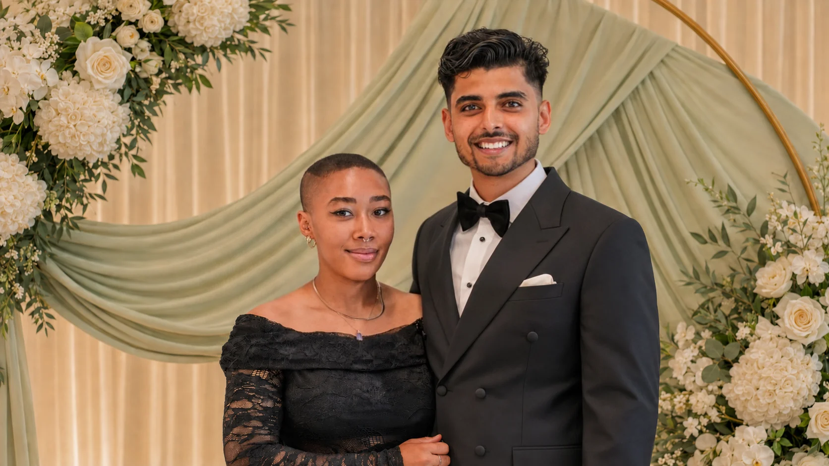 Akshat and Jade standing together as newlyweds beneath their floral wedding arch